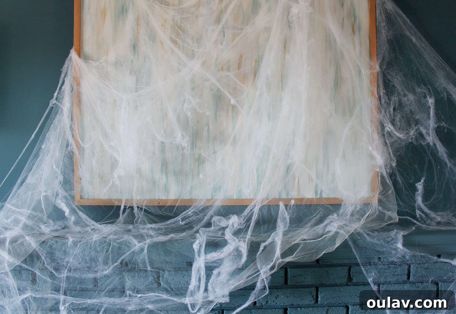 Eerie Elegance: DIY Spiderweb Halloween Mantel 7 Fake Spiderwebs Artfully Arranged on Blue Mantel