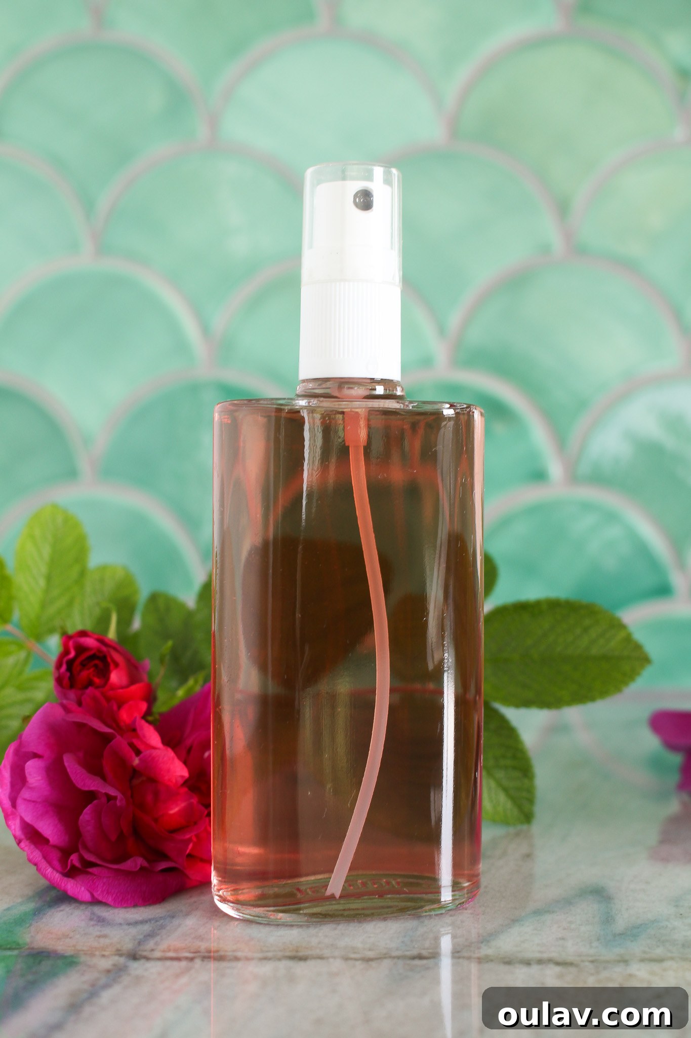Radiant Roses: DIY Simmered Facial Mist 14 A spray bottle of homemade rose water being spritzed onto hands, with fresh roses in the background.