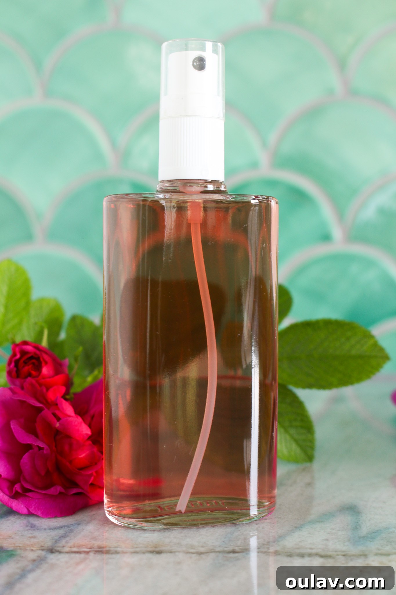Radiant Roses: DIY Simmered Facial Mist 10 A glass spray bottle of rose water misted onto skin.