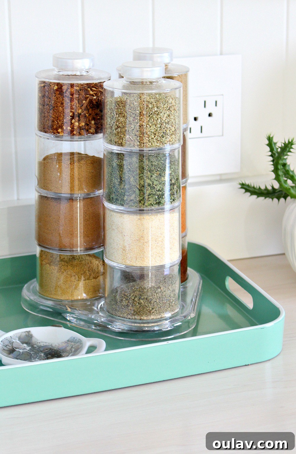 Colorful KitchenAid utensils in a glass vase on a kitchen counter, next to a modern spice tower.