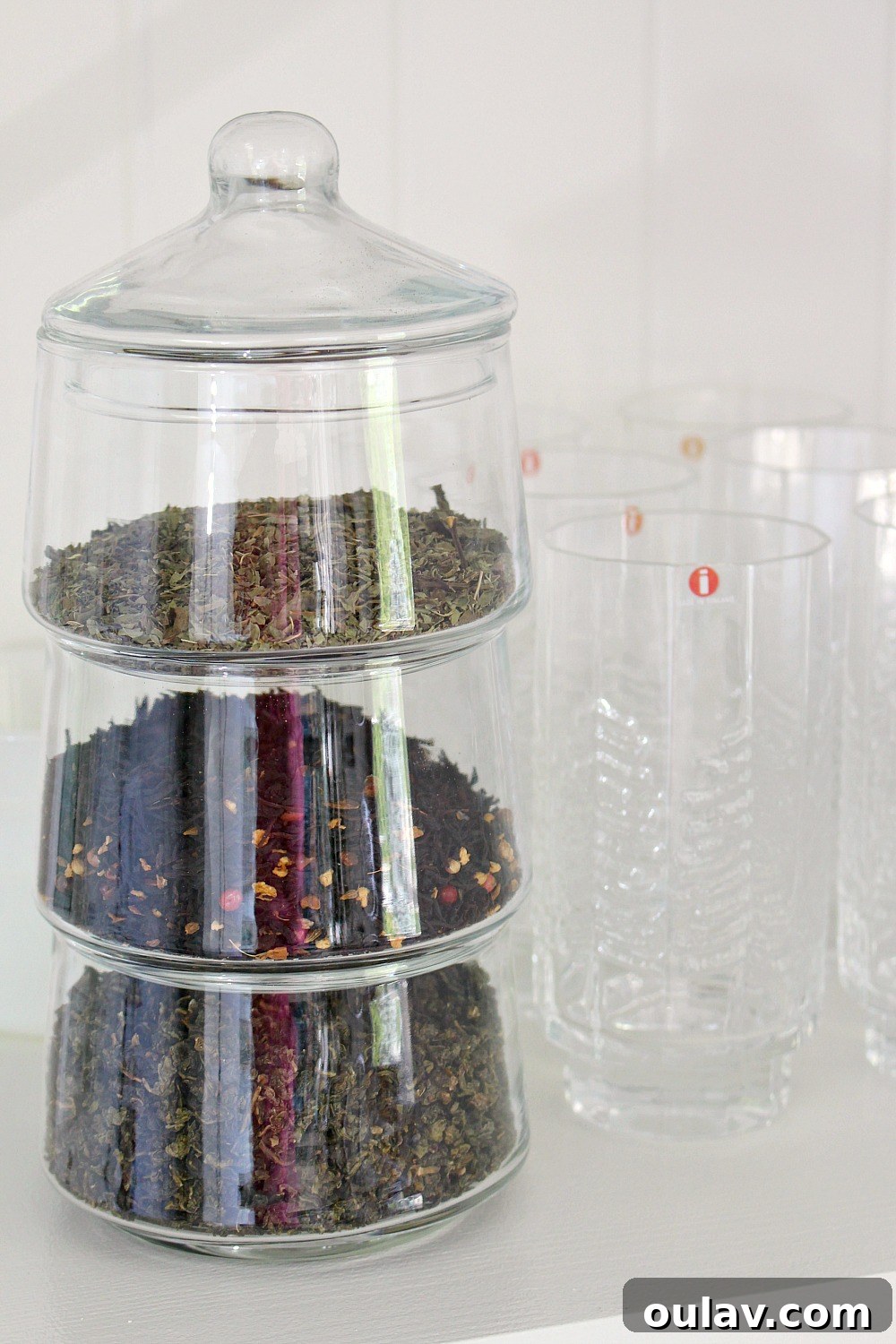 Close-up of a modern spice tower on a kitchen counter, next to a vibrant turquoise kitchen wall.