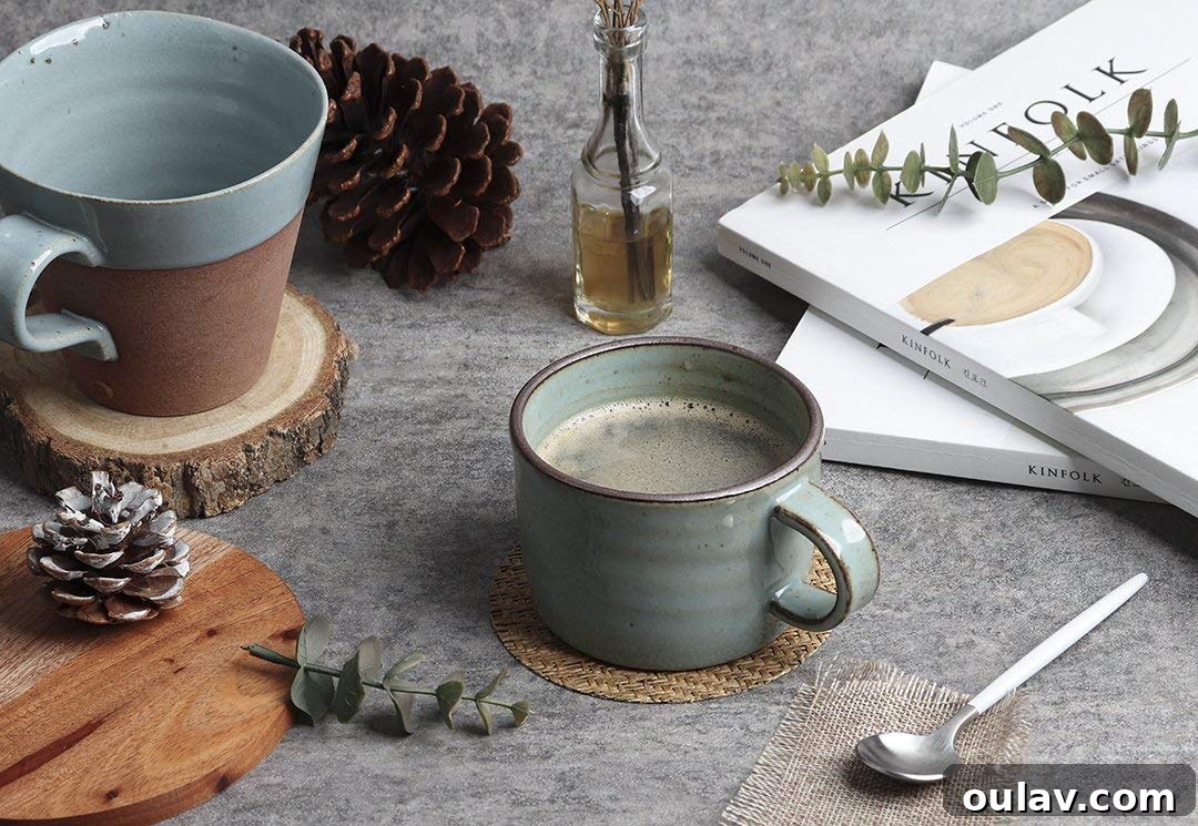 Holiday Haven: 25 Delightful Gifts for Homebodies 12 A collection of handmade pottery mugs in various colors, alongside a tea bag and spoon, perfect for cozy drinks.
