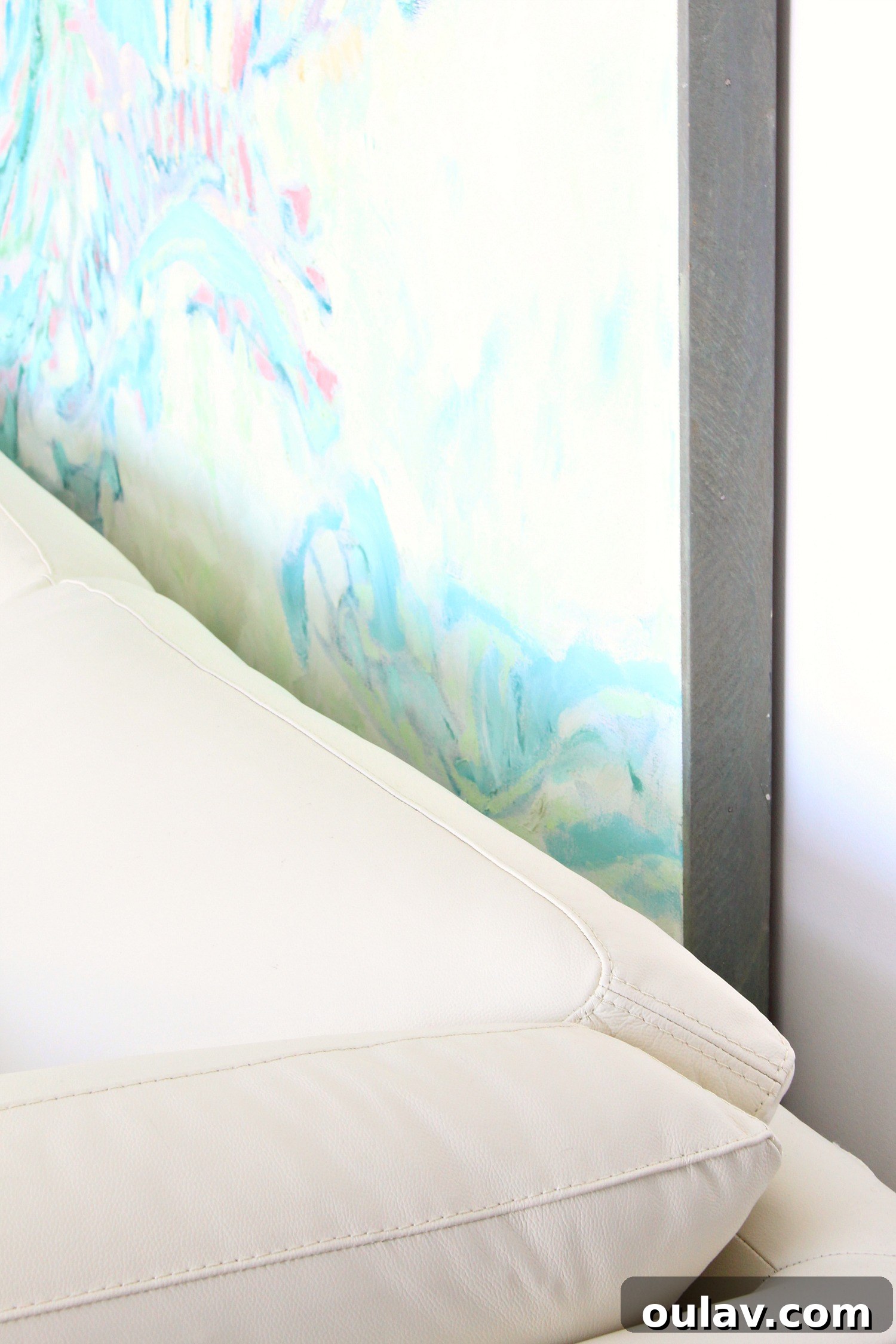 Close-up of the gap between the sofa and the large painting, demonstrating the protective spacing solution.