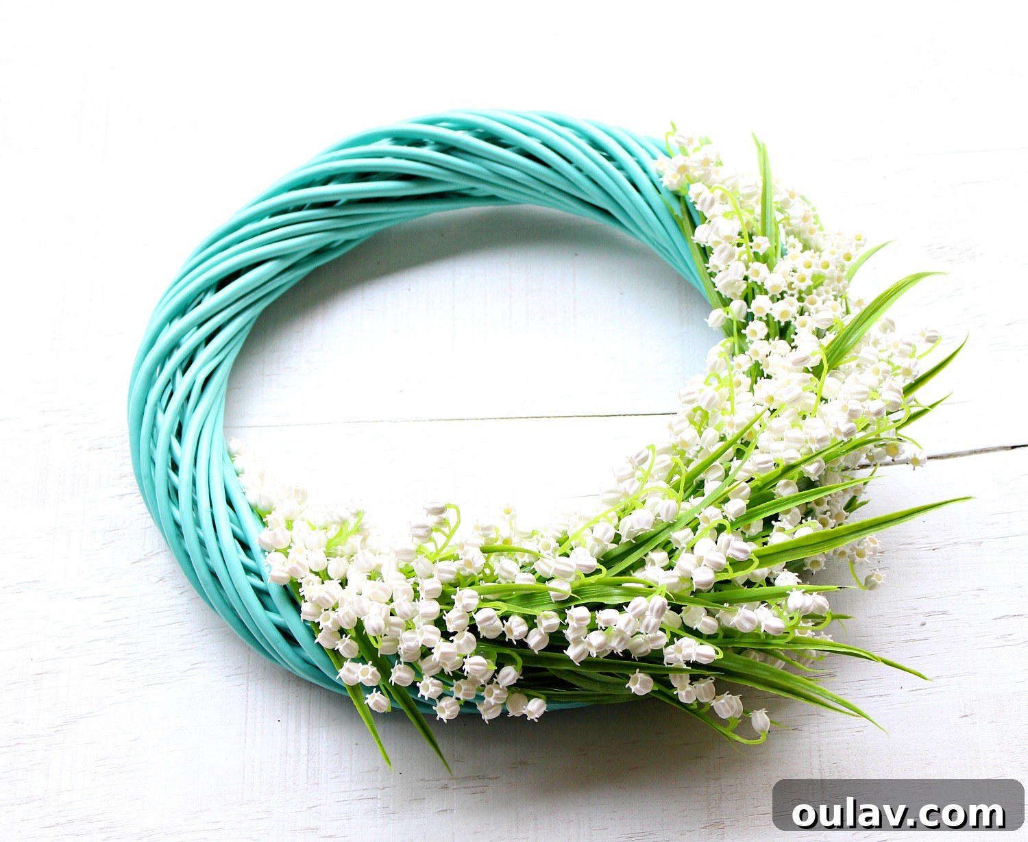 Effortless Turquoise Lily Faux Wreath 13 Hot glue gun securing faux flowers to a turquoise wreath form