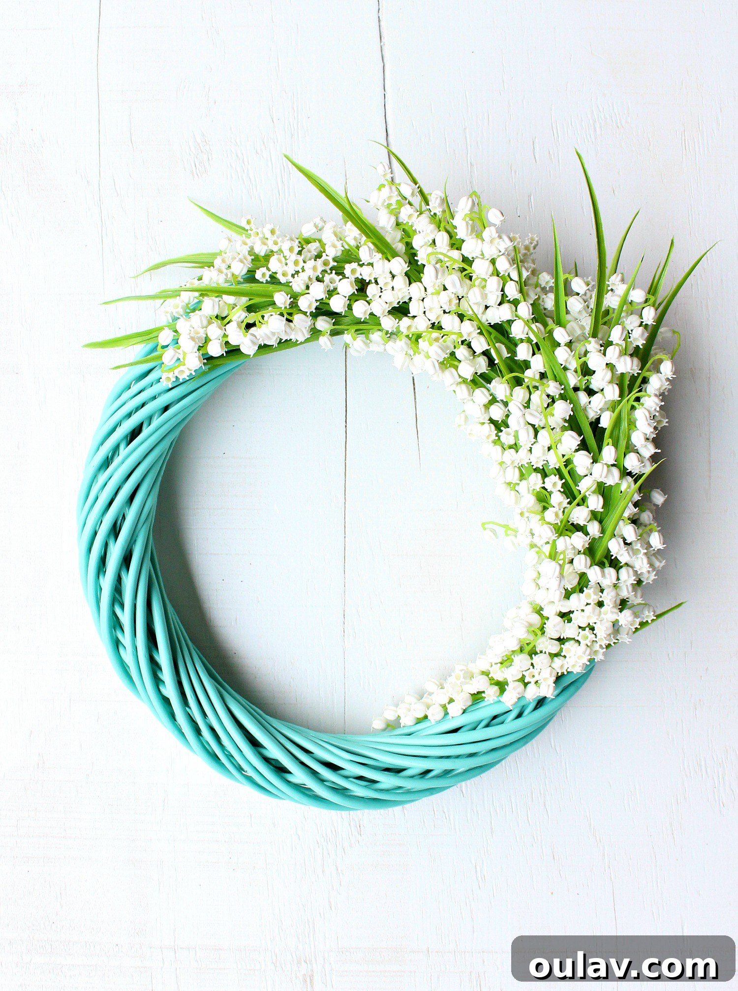 Effortless Turquoise Lily Faux Wreath 14 Arranging individual faux Lily of the Valley stems to hide hot glue on the wreath