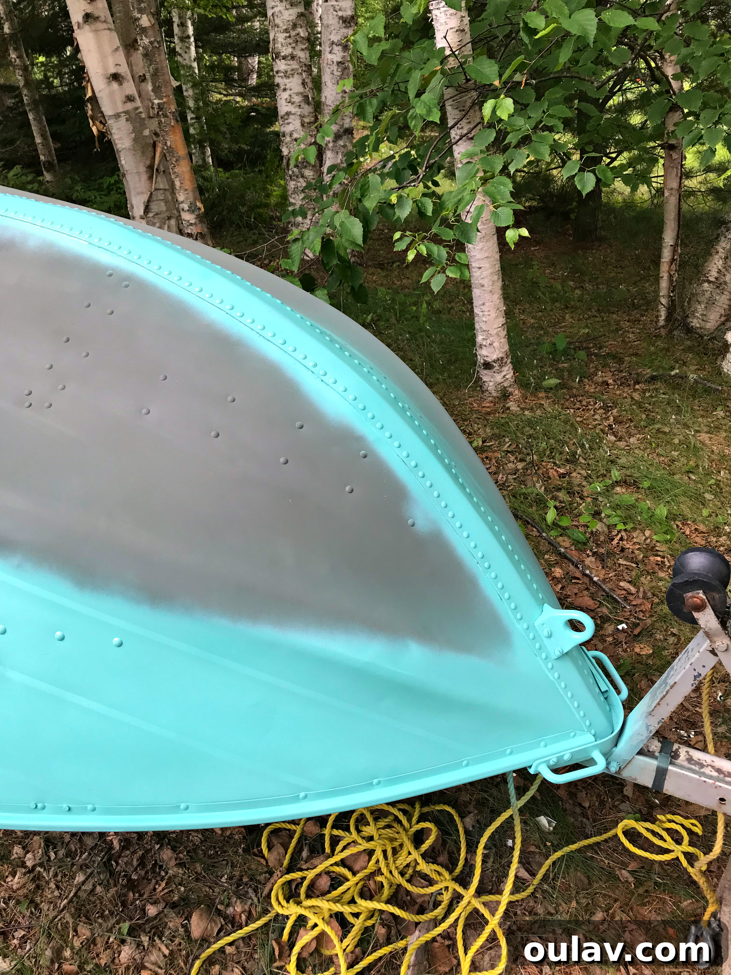 Spraying the first thin coat of turquoise lacquer onto the primed aluminum boat exterior.
