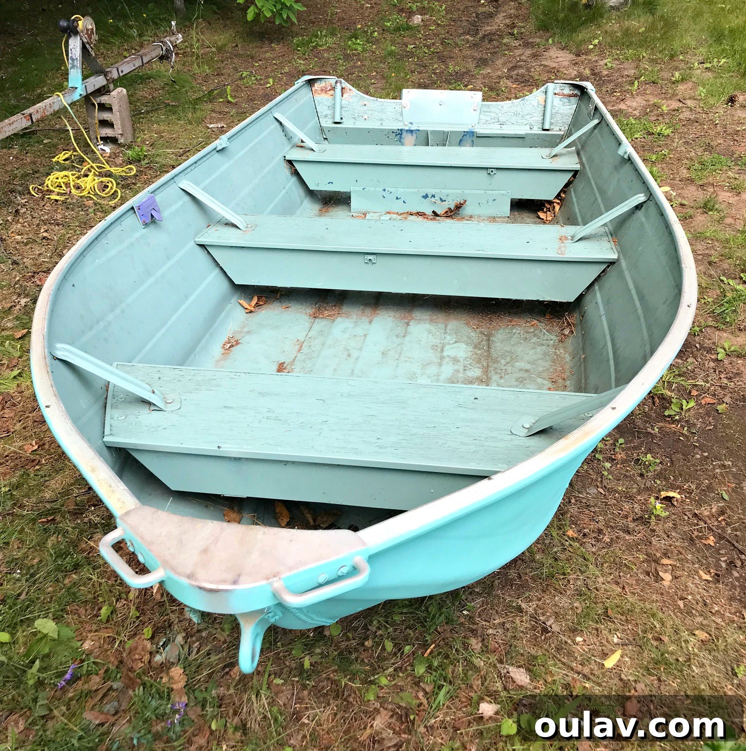 Cleaning out the boat's interior with a shop vac, removing debris before painting.