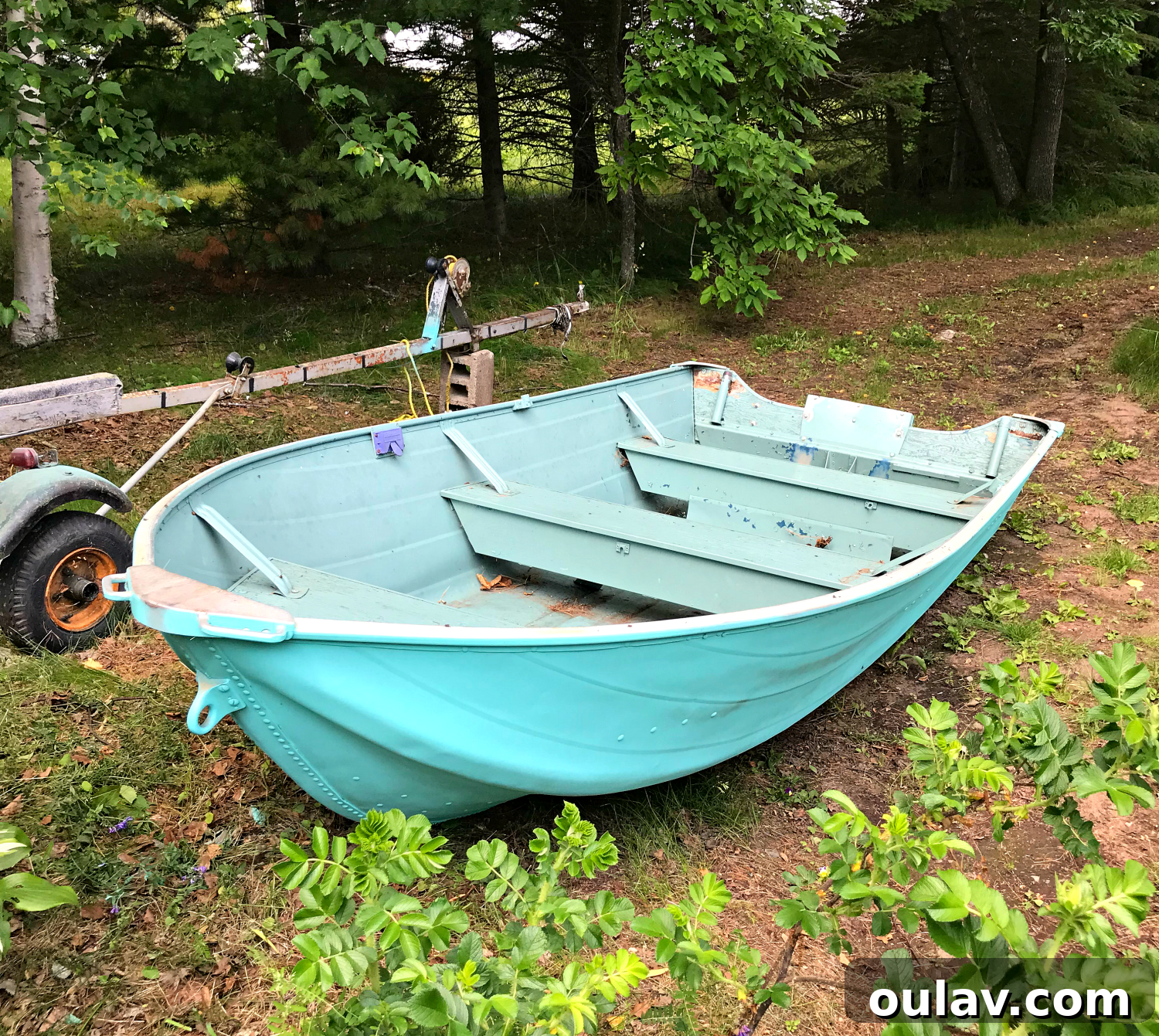 Sanding the interior surfaces of the aluminum boat with a drill attachment to prepare for new paint.