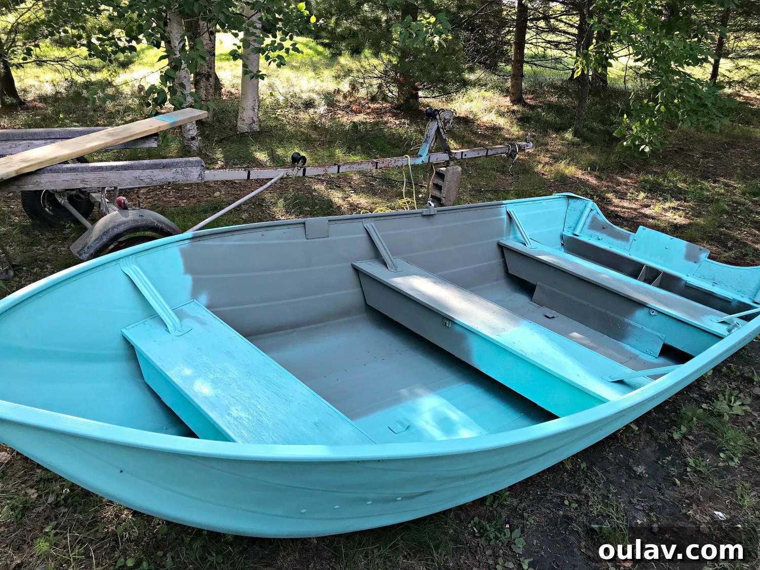Applying turquoise lacquer to the interior of the aluminum boat, ensuring full coverage.