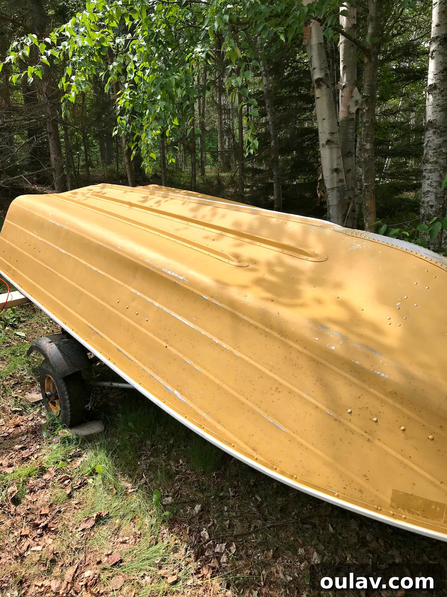 Close-up of the old aluminum boat's faded yellow exterior before painting.