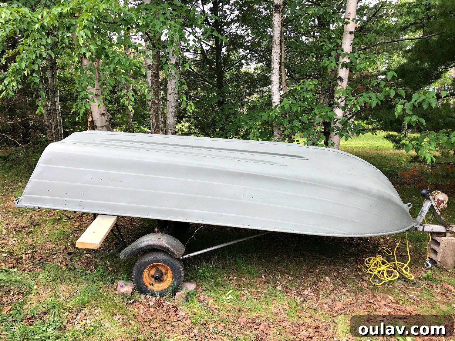 Applying Rust-Oleum Self-Etching Primer to the aluminum boat's exterior with steady, even strokes.