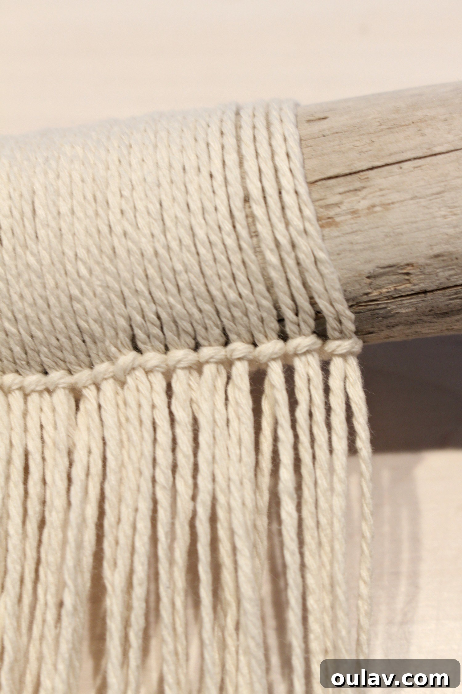 A close-up view of the evenly spaced strings attached to the driftwood, before knotting.