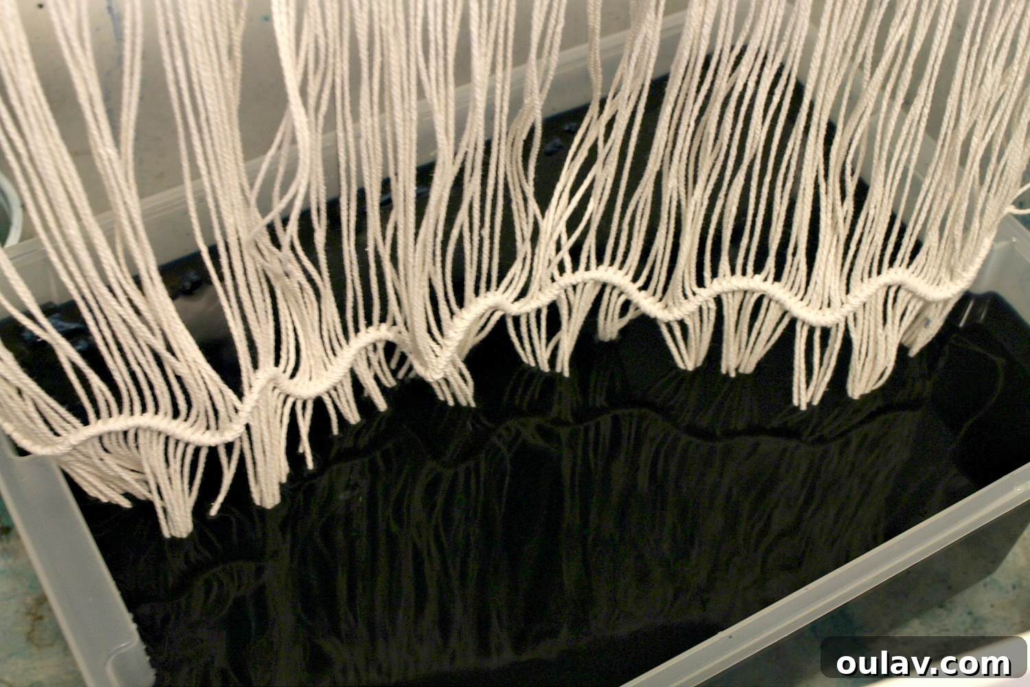 Handcraft Your Own Macrame Driftwood Wall Art 26 Two images showing the dip-dyeing process for the macrame wall hanging, with the string ends immersed in dye.
