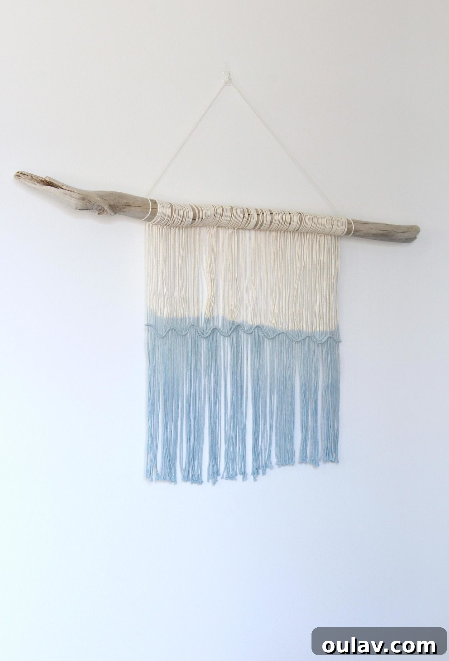 A close-up shot of the macrame knots creating a wave pattern on the driftwood wall hanging.